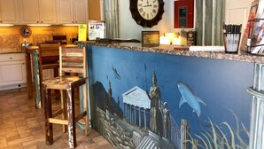Une cuisine avec une horloge, une fresque murale et un comptoir sur lequel sont disposés divers objets.
