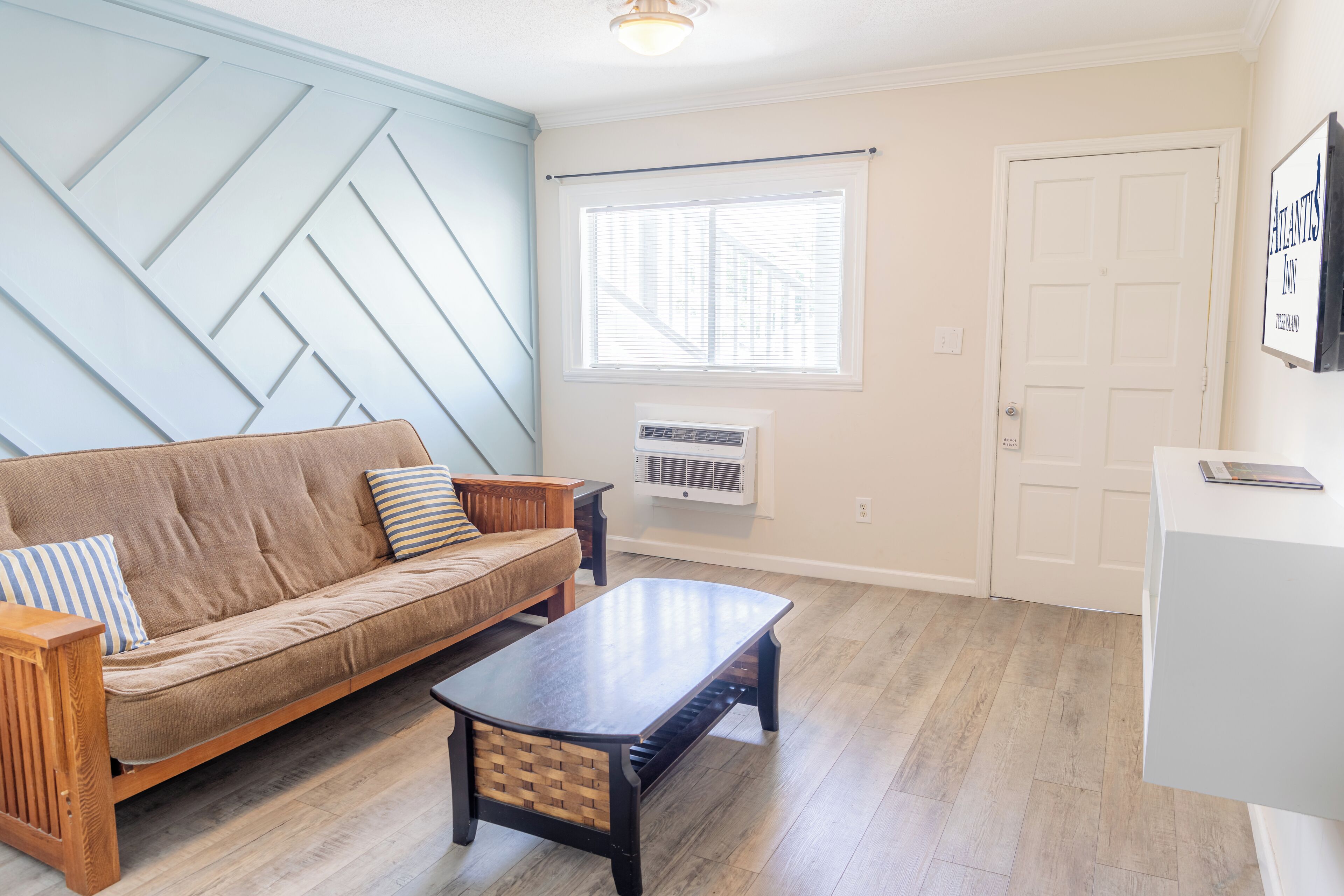 A living room with a sofa, coffee table, and a window with blinds.
