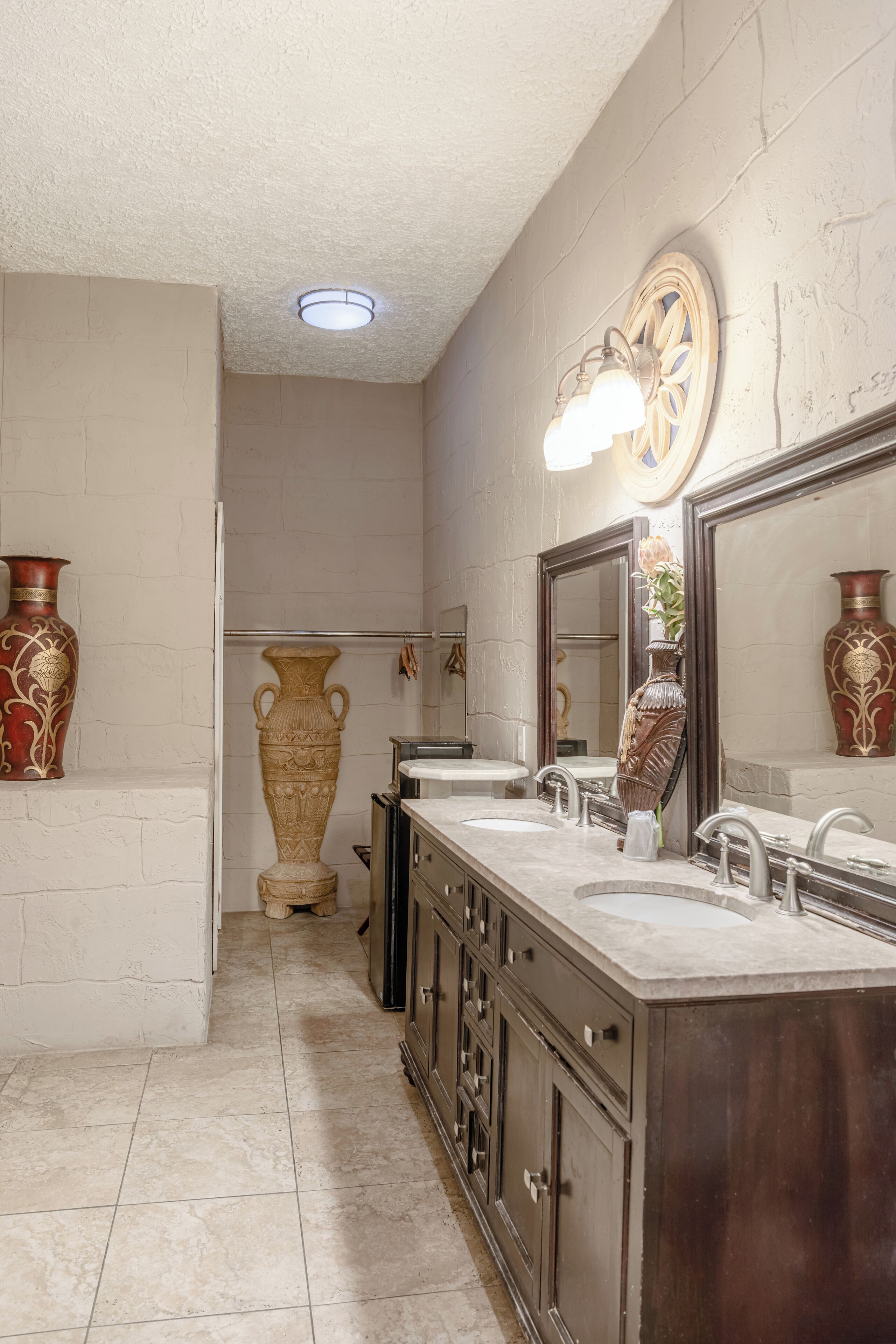 Un baño con tocador doble, un espejo grande y jarrones decorativos.