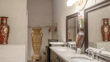 Un baño con tocador doble, un espejo grande y jarrones decorativos.