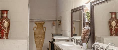 Un baño con tocador doble, un espejo grande y jarrones decorativos.