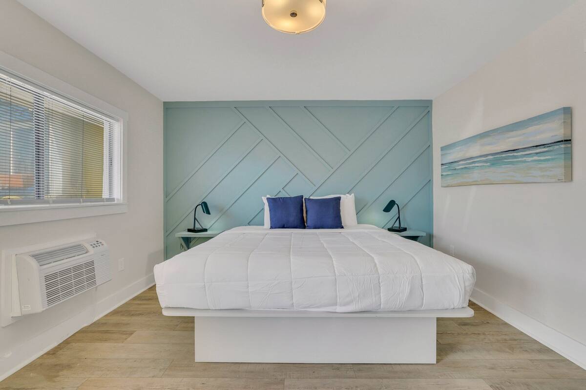 Une chambre moderne avec un grand lit, un radiateur fixé au mur, une fenêtre avec des stores et un tableau accroché au mur.
