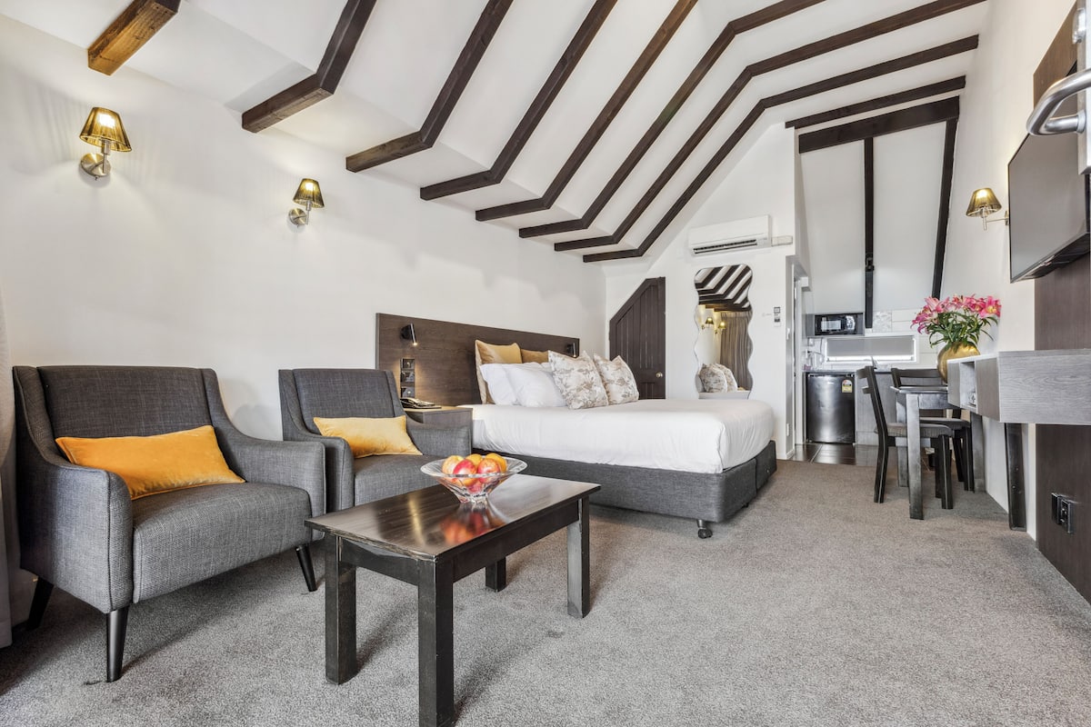 Una habitación de hotel moderna con sofá, sillón y zona de comedor.