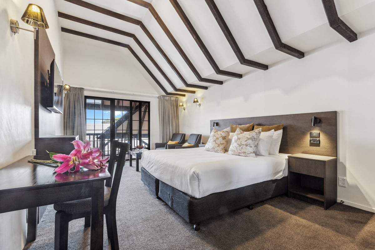 Una habitación de hotel moderna con una cama grande, un escritorio con una silla y vistas al exterior.