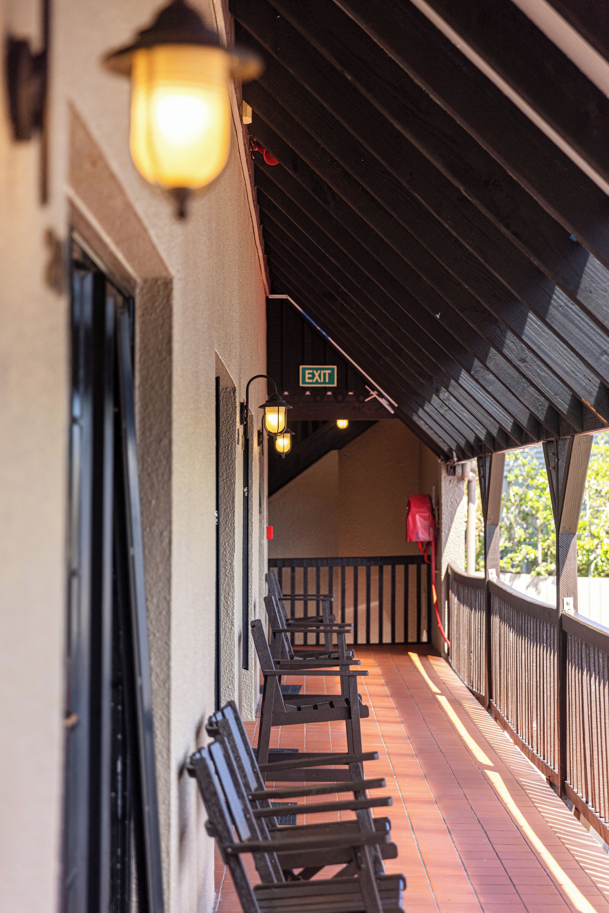 A covered outdoor seating area with benches, a railing, and a sign indicating an exit.