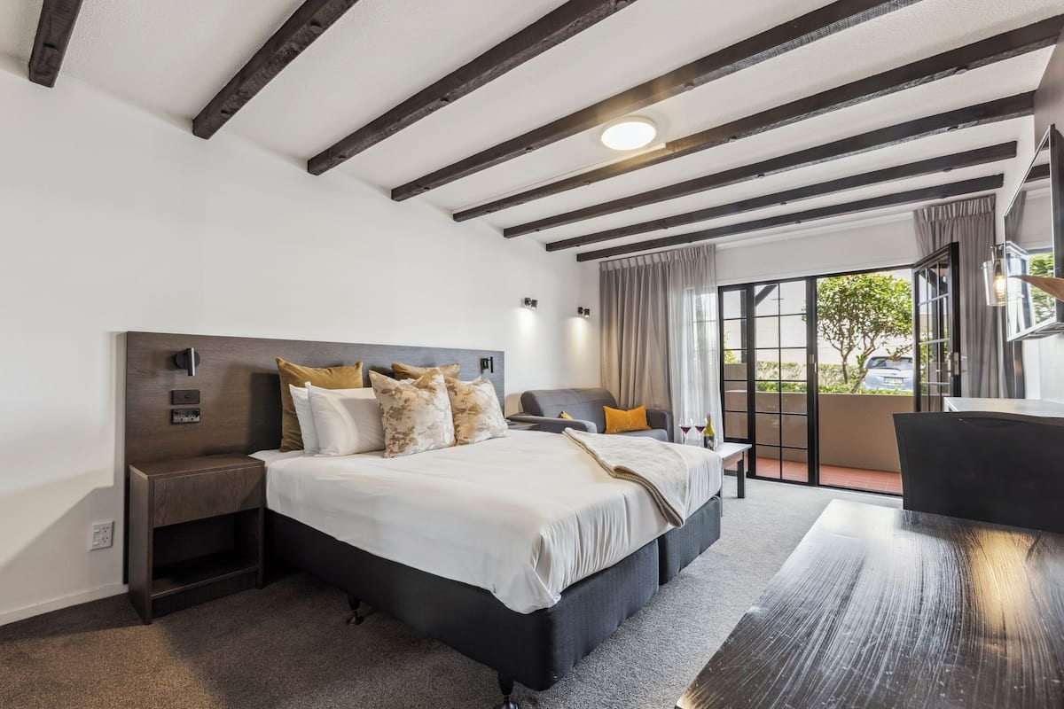 Una habitación de hotel moderna con una cama grande, una mesita de noche, un escritorio y vistas al exterior.