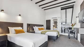 Una habitación de hotel moderna con dos camas, una kitchenette y un televisor.