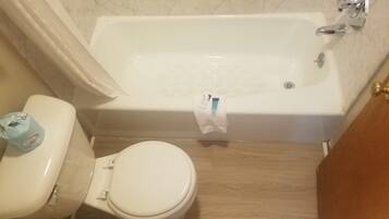 Un baño con inodoro, bañera y piso de madera.