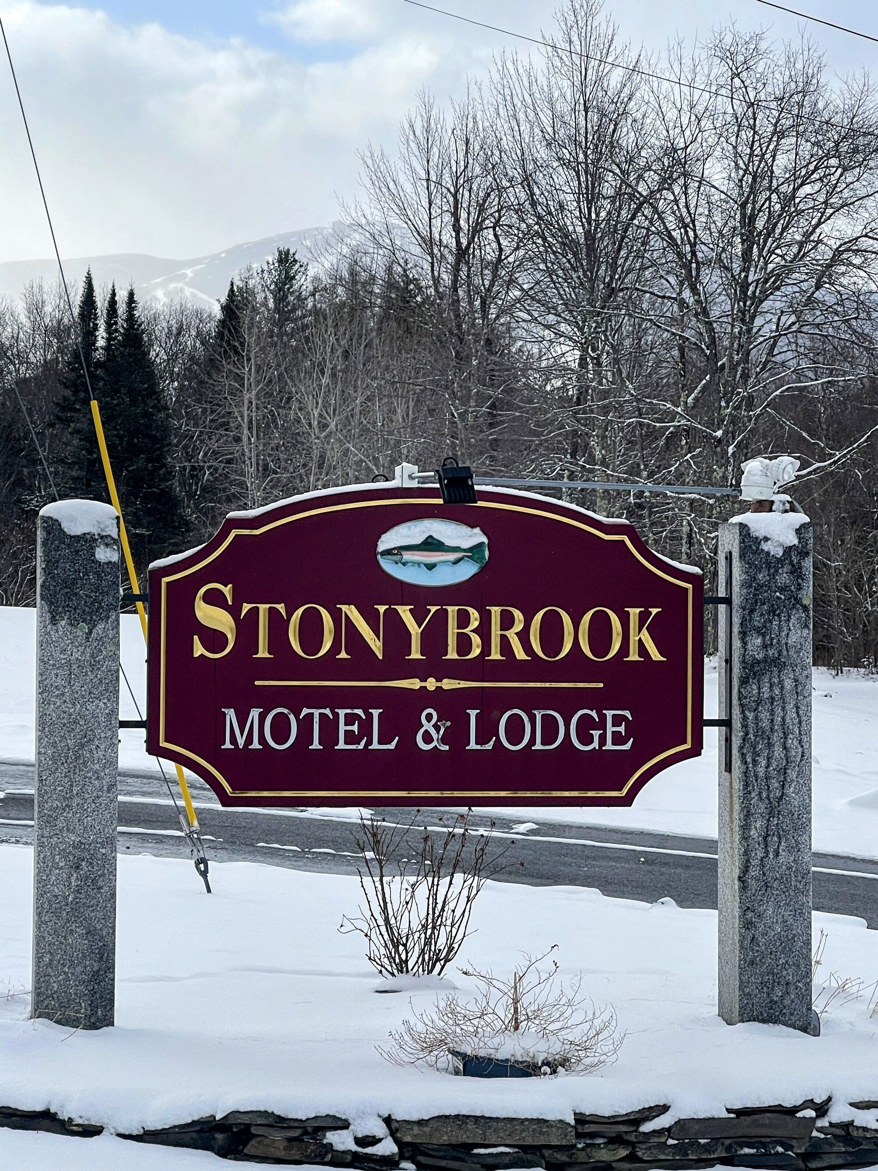 A sign for Stonybrook Motel & Lodge with a mountain backdrop.