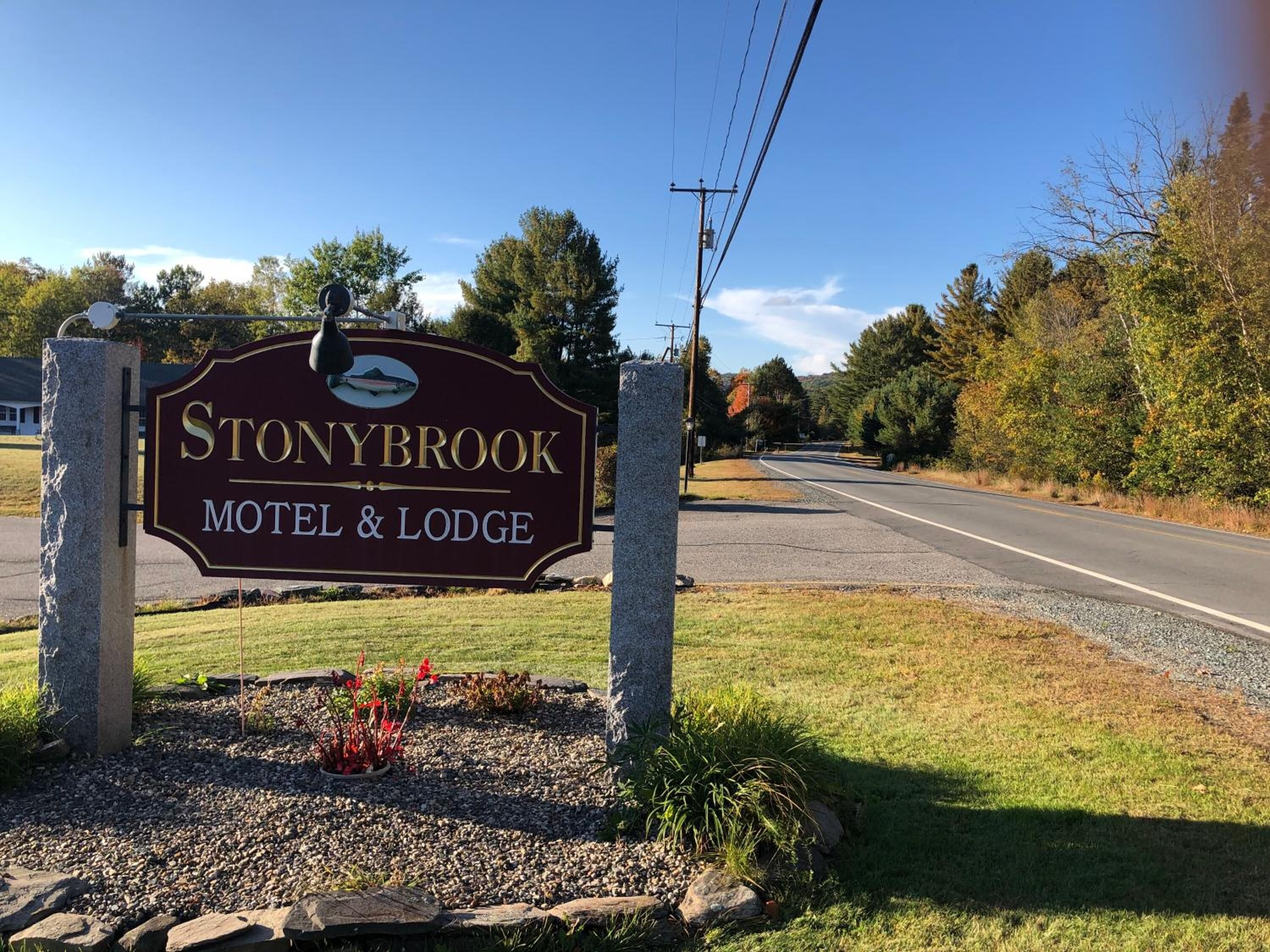 Señal del motel y cabañas Stonybrook & Lodge, con una carretera despejada y árboles al fondo.