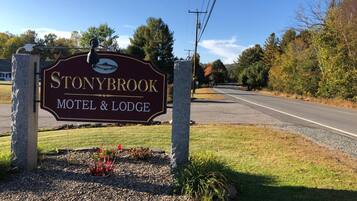 Señal del motel y cabañas Stonybrook & Lodge, con una carretera despejada y árboles al fondo.
