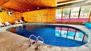 An indoor swimming pool with wooden walls and ceiling, surrounded by lounge chairs. - Stonybrook Motel & Lodge (Franconia)
