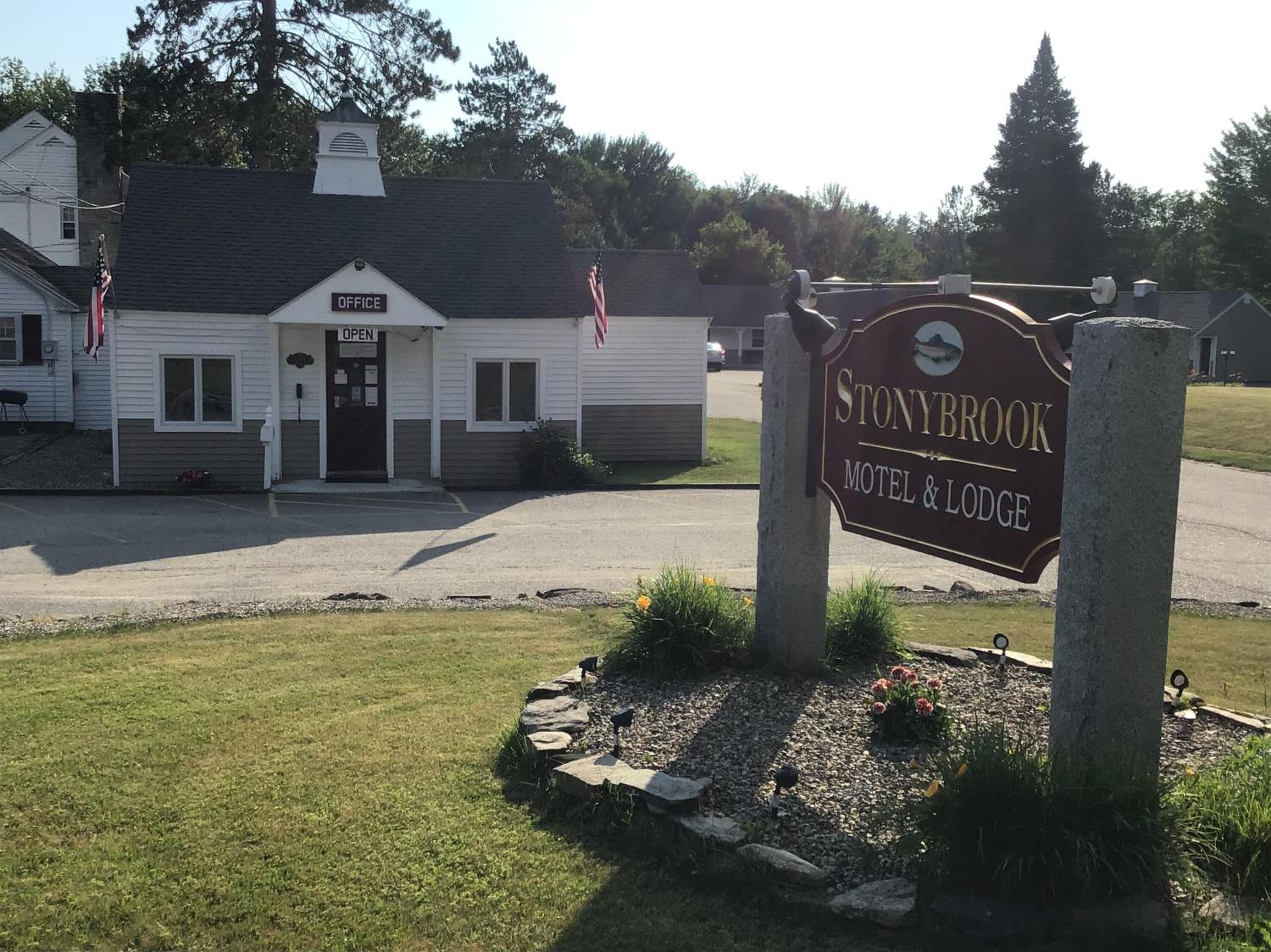 A sign for Stonybrook Motel & Lodge with a white building in the background.
