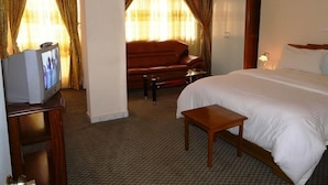Una habitación de hotel con cama, televisión, sofá y una mesita.