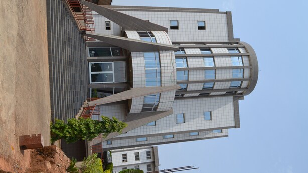 Un edificio moderno con un diseño arquitectónico único, que destaca por una fachada curva y numerosas ventanas.