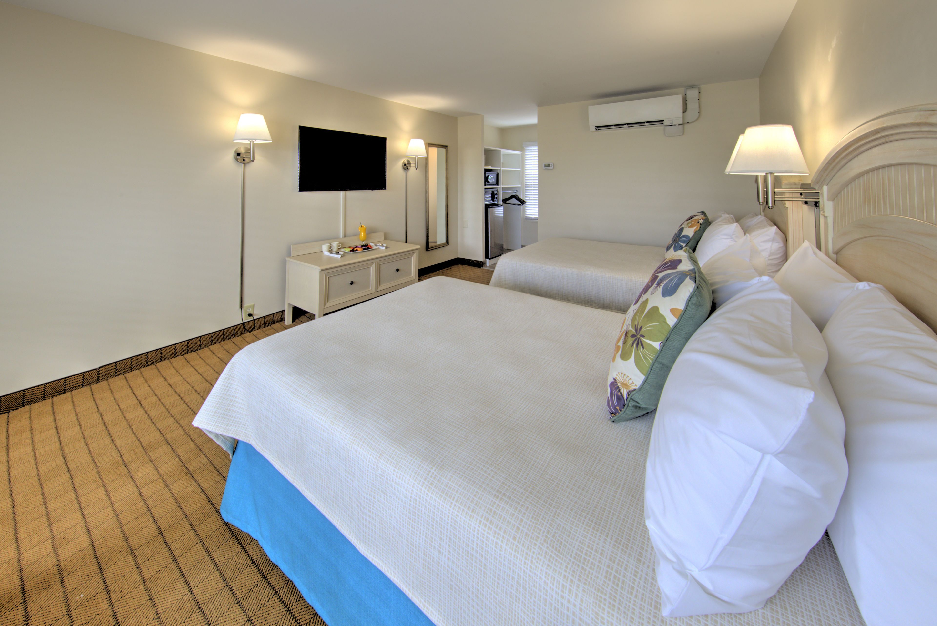 Habitación de hotel con dos camas, un escritorio, un televisor y un equipo de aire acondicionado.