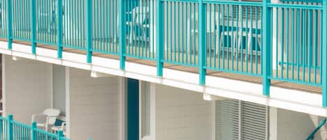 A multi-story building with balconies, white walls, and turquoise railings.