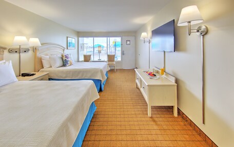 A hotel room with two beds, a desk, a TV, and a window with a view.