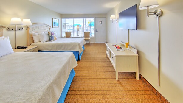 A hotel room with two beds, a desk, a TV, and a window with a view. - Dunes Court (Ocean City)