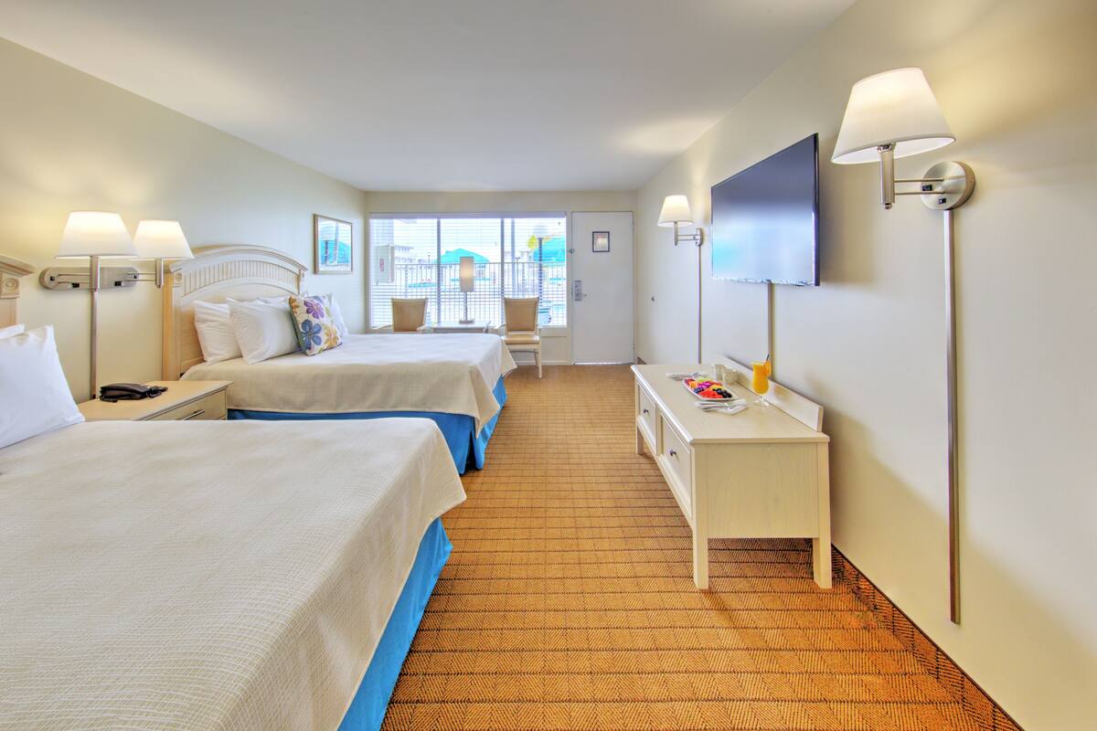 Une chambre d’hôtel avec deux lits, un bureau, une télévision et une fenêtre donnant sur un paysage agréable.