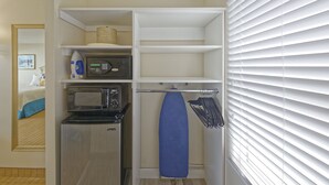 A compact kitchen with a microwave, a small refrigerator, and a hanging rack. - Dunes Court (Ocean City)