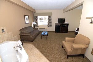 Habitación de hotel con sofá, sillón, televisión y una mesita.