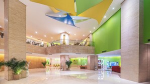 A spacious lobby with a high ceiling, a central staircase, and a reception area.