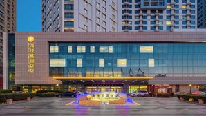 A modern hotel building with a large glass facade and a well-lit entrance.