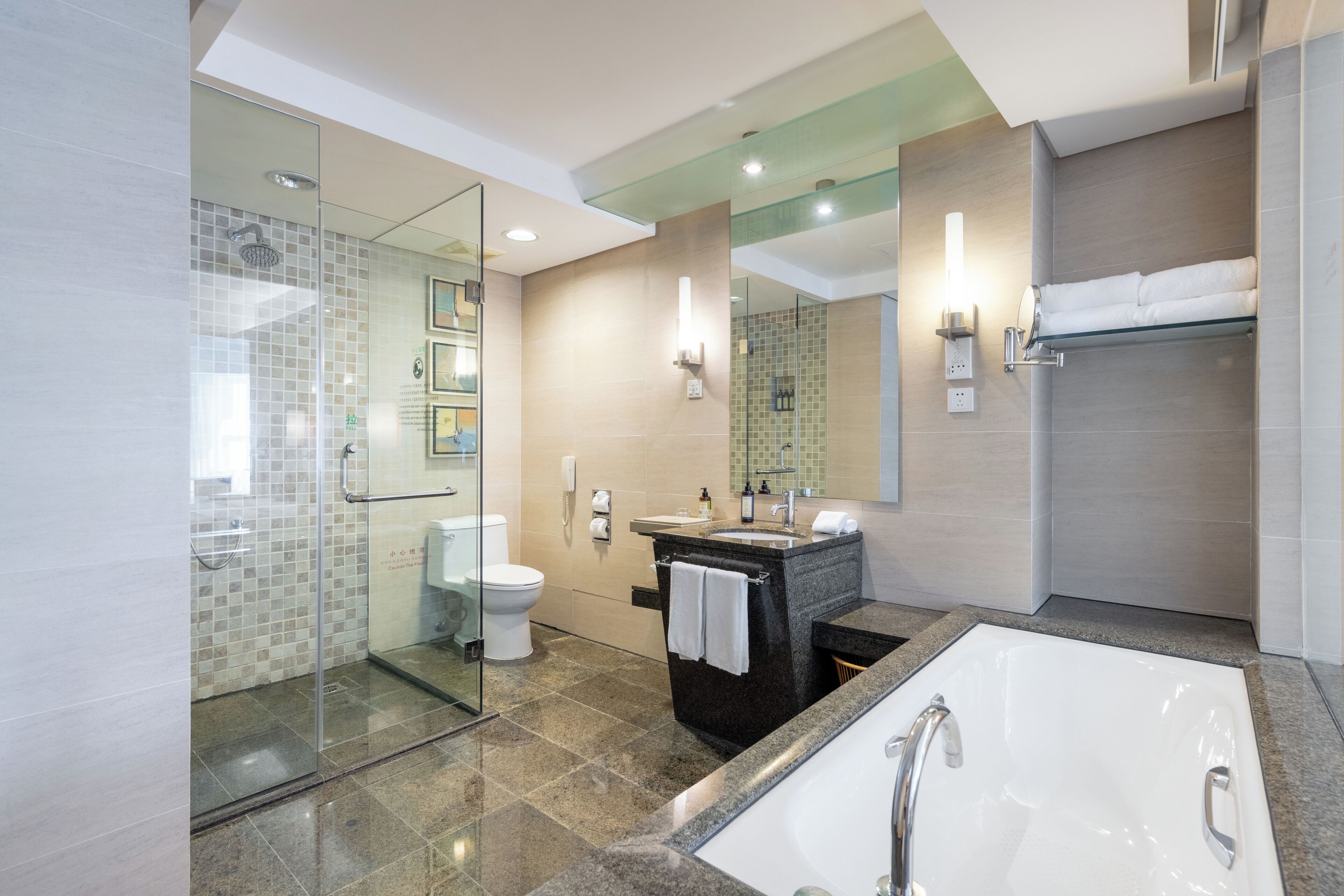 Un baño moderno con cabina de ducha de vidrio, una bañera independiente, un tocador con espejo y un perchero para toallas.
