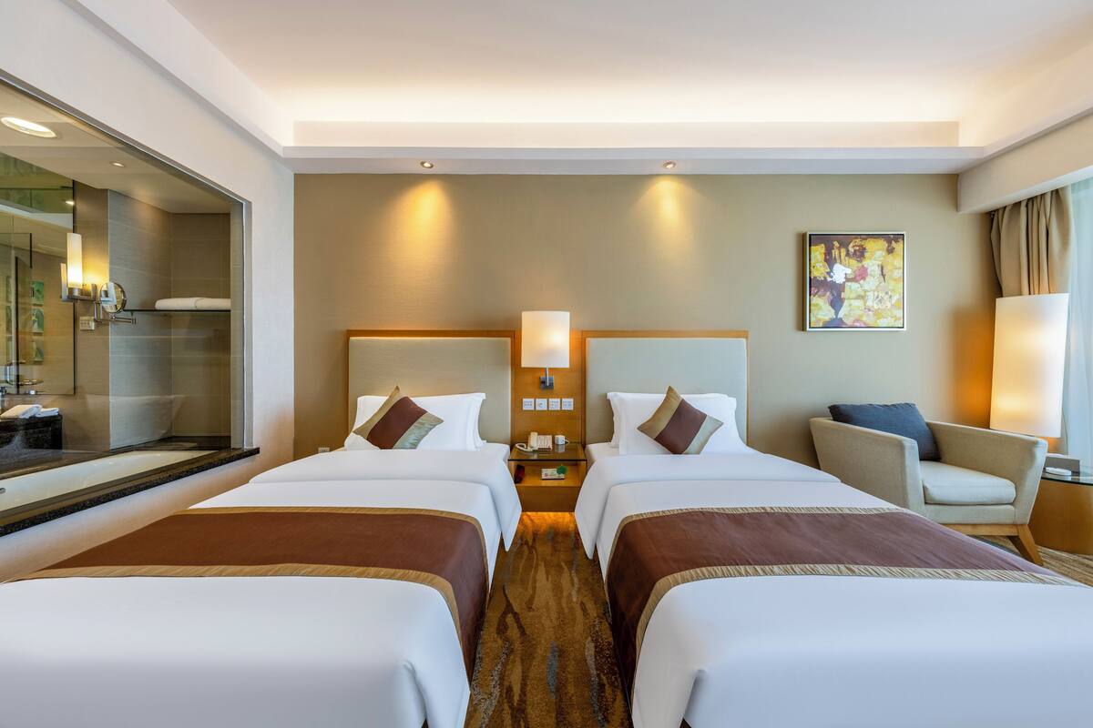Een hotelkamer met twee bedden, een nachtkastje, een stoel en een grote spiegel.