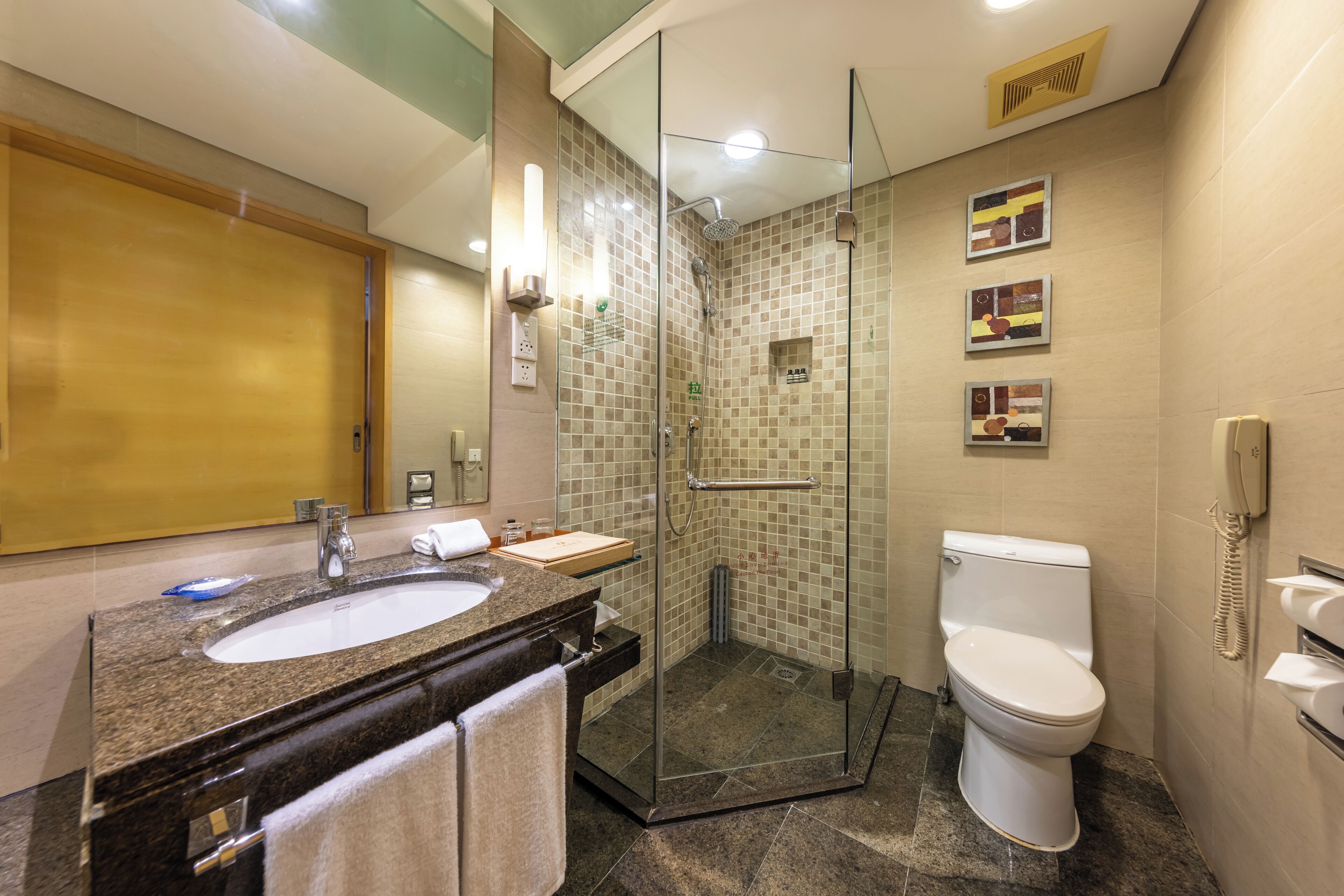 Un baño moderno con ducha de vidrio, lavamanos con encimera de mármol y retrete.