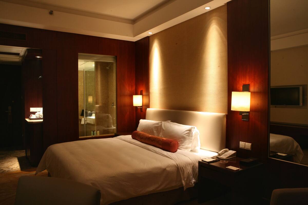 Une chambre d’hôtel avec un grand lit, des lampes de chevet, un téléphone et un miroir au mur.