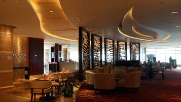 A spacious lobby with modern furniture, a reception desk, and a large window providing natural light.