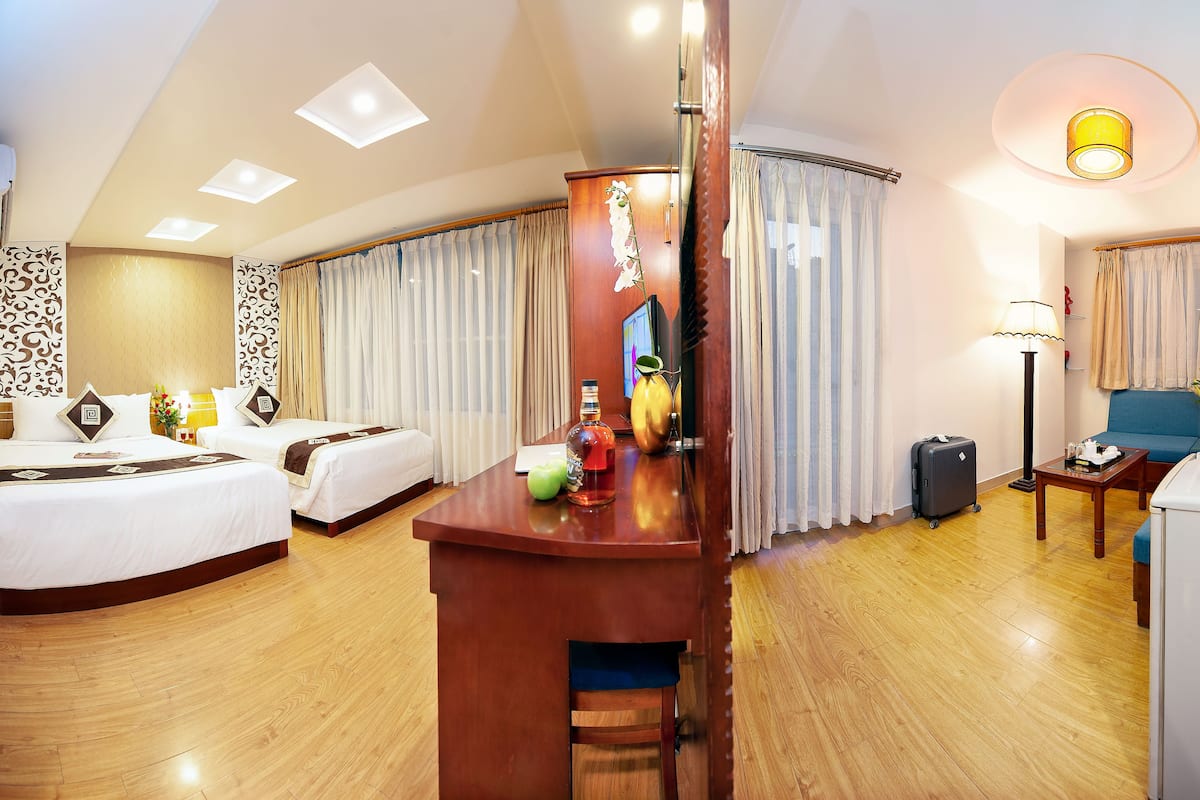 Ein Hotelzimmer mit zwei Betten, einem Schreibtisch, einem Stuhl, einer Lampe, einem Koffer und einem Fernseher.