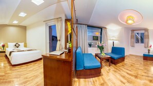 Een hotelkamer met een bed, een bureau, een blauwe bank, een kleine tafel en een raam met gordijnen.