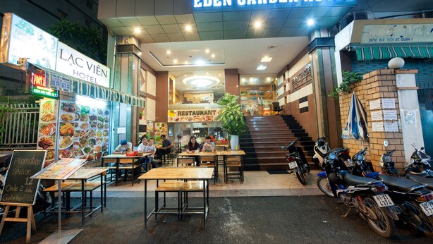 De buitenkant van Hotel Eden Garden met een restaurant, een eetgedeelte en motorfietsen die ervoor geparkeerd staan.