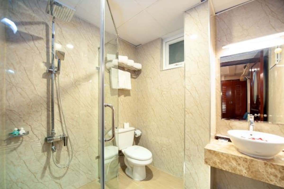 Une salle de bain avec une douche à parois de verre, des toilettes et un lavabo avec un miroir au-dessus.