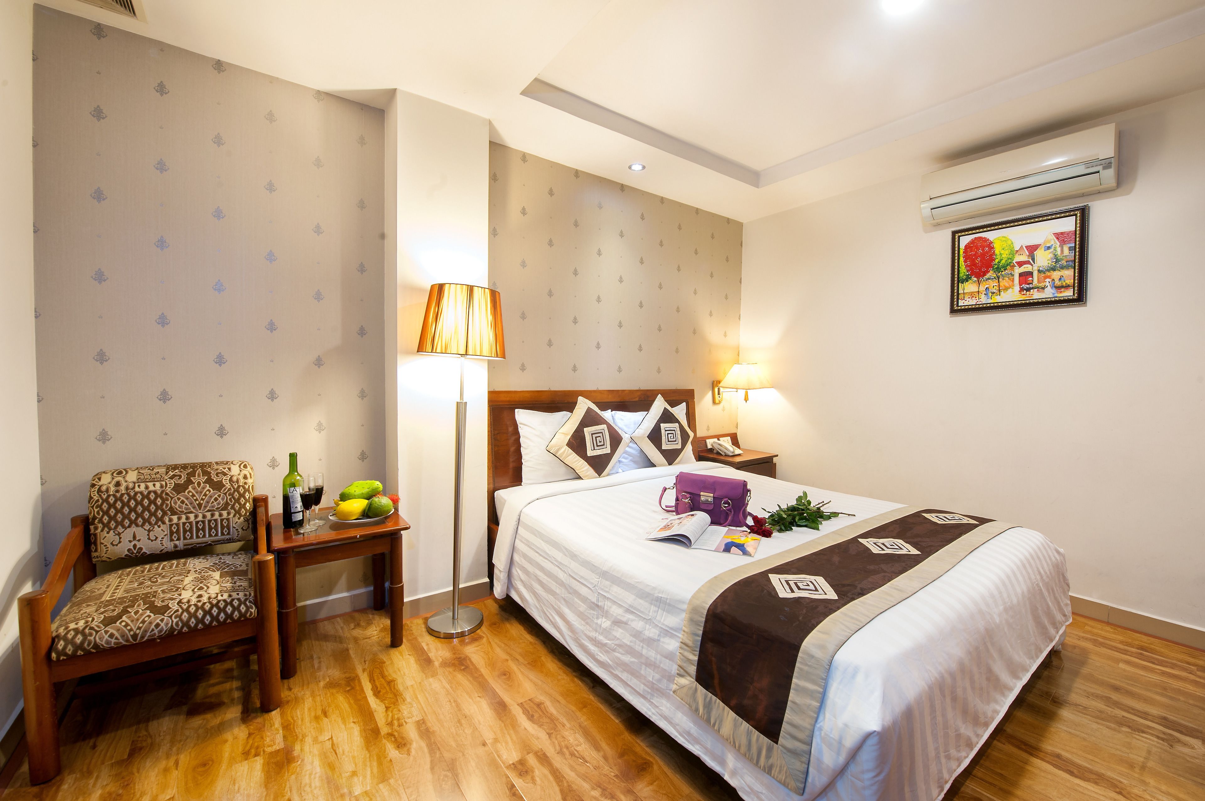 Une chambre d’hôtel comprenant un lit, une chaise, une table de chevet, une lampe et un climatiseur fixé au mur.