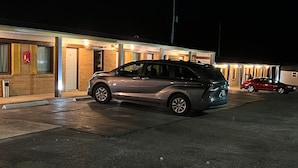 Un edificio con estacionamiento y dos coches aparcados al frente.