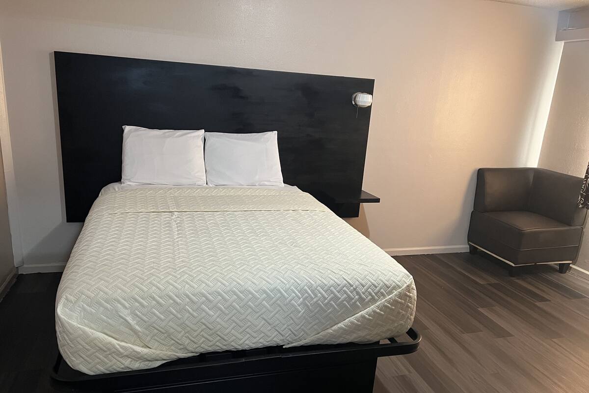 Un lit recouvert d’une couette blanche matelassée, avec une tête de lit noire et deux oreillers blancs.