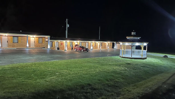 Un motel con estacionamiento techado y un pequeño pabellón.