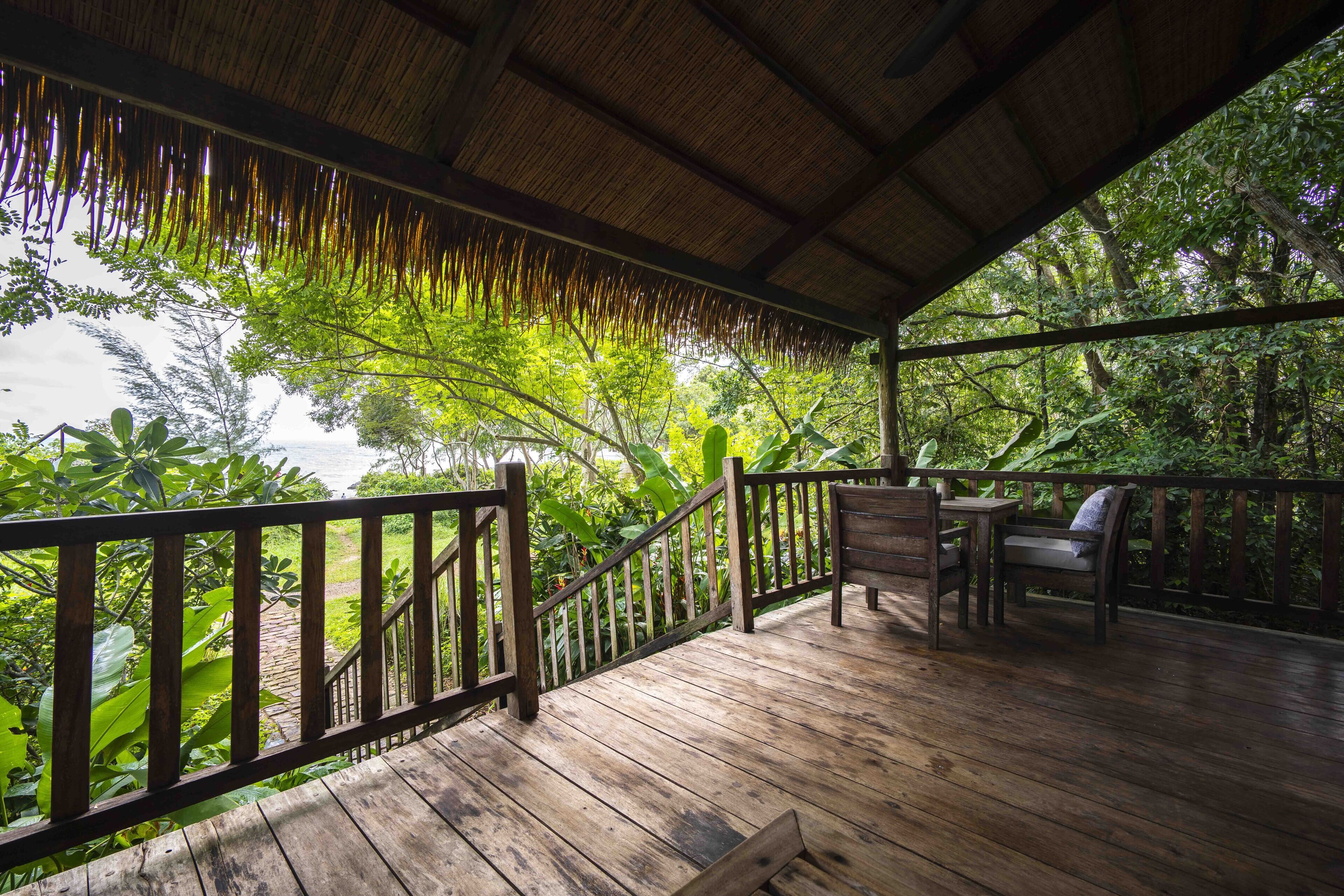 A wooden deck with a railing, a bench, and a table.