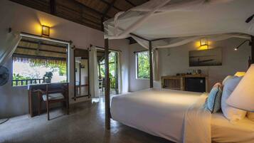 A bedroom with a bed, bedside table, lamp, and a view of the outdoors.