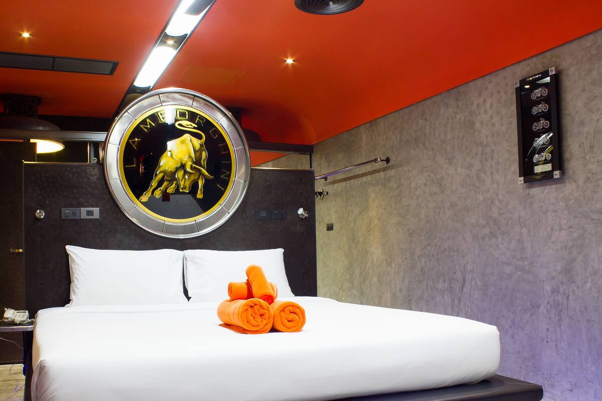 A modern hotel room with a bed, a round mirror, and a wall-mounted TV.
