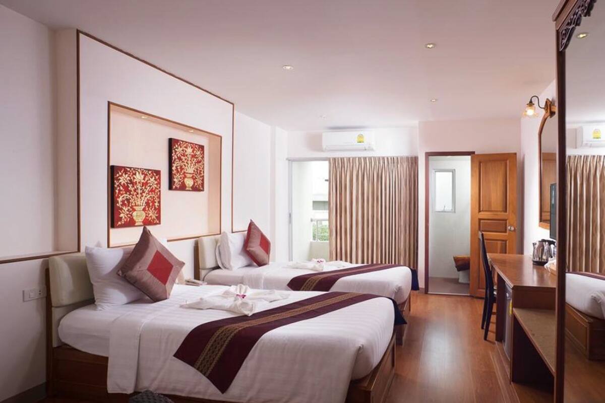 A hotel room with two beds, a desk, and a mirror.