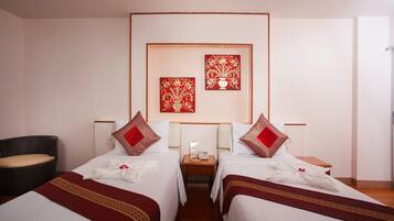 A hotel room with two beds, a small bedside table with a phone, and a chair.