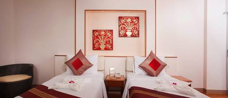 Quarto de hotel com duas camas, uma mesa de cabeceira pequena com telefone e uma cadeira.