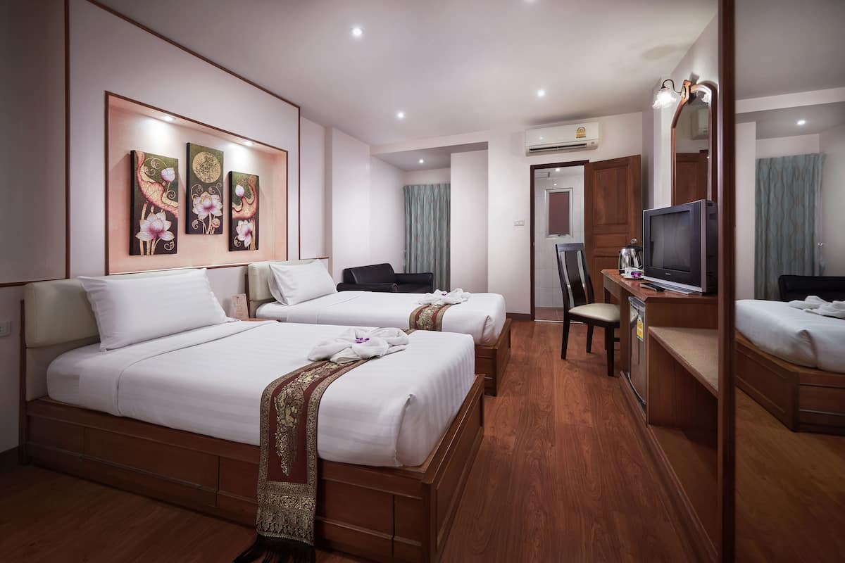 A hotel room with two beds, a desk with a TV, a chair, and a mirror.