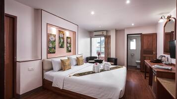 A hotel room with a large bed, a desk with a chair, a bathroom, and a view of the city.