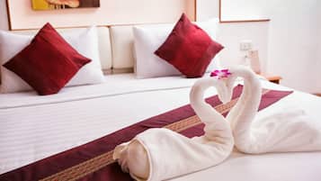 Habitación de hotel con una cama bien hecha, almohadas rojas y blancas, y una decoración de toallas sobre la cama.